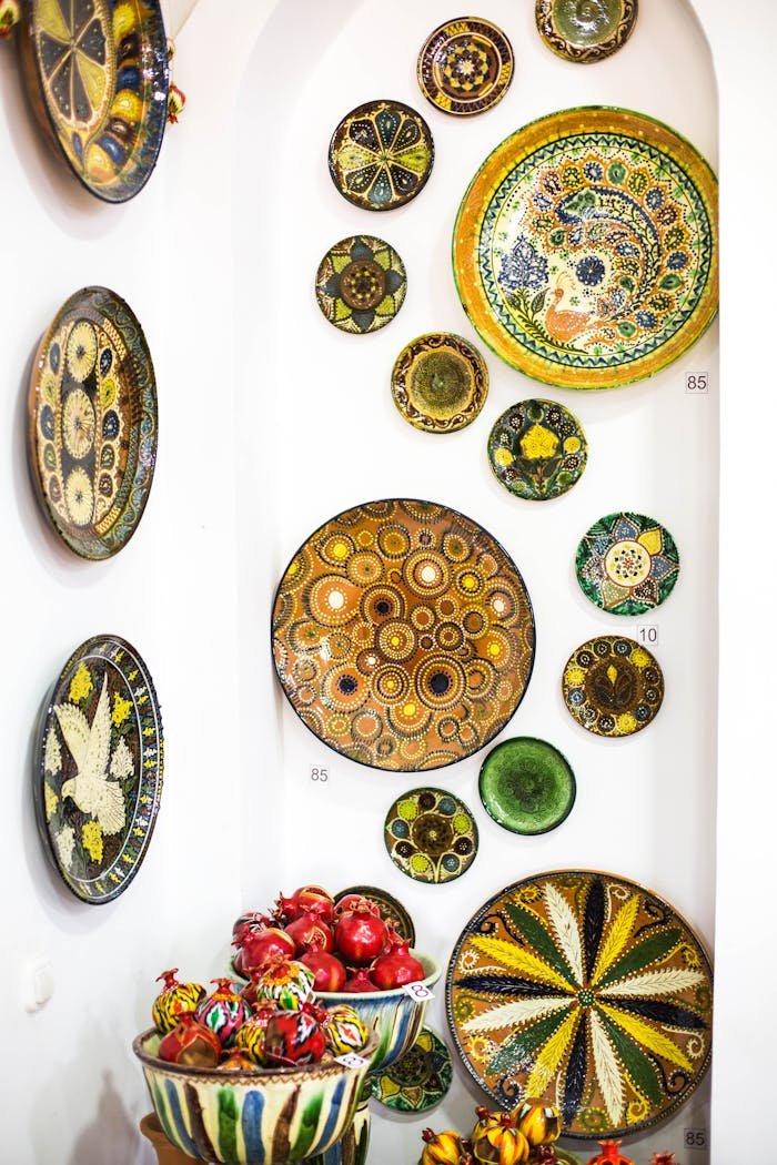 Colorful traditional ceramic plates displayed on a white wall in Gijduvon, Uzbekistan.