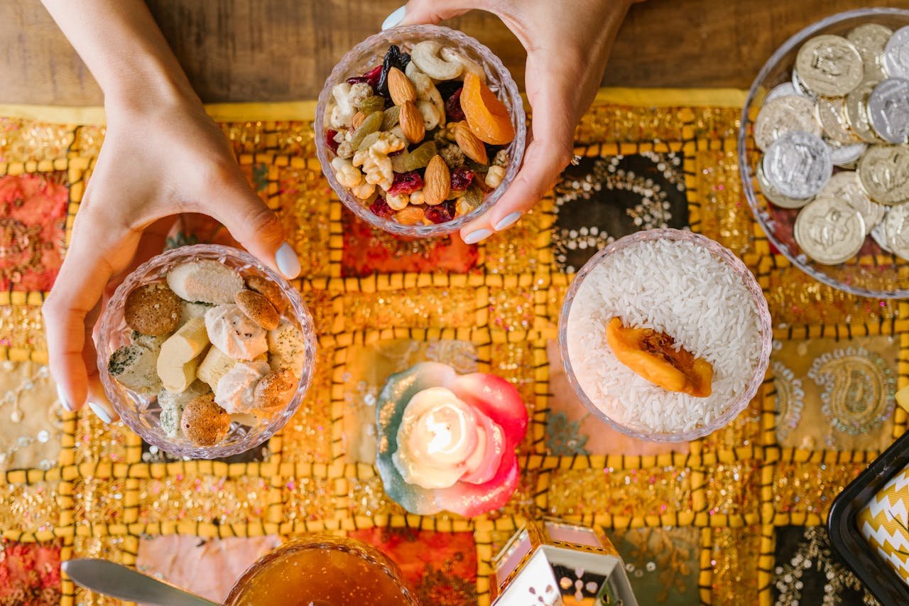 Hands arranging traditional Persian snacks for Nowruz on a decorated table with candlelight.